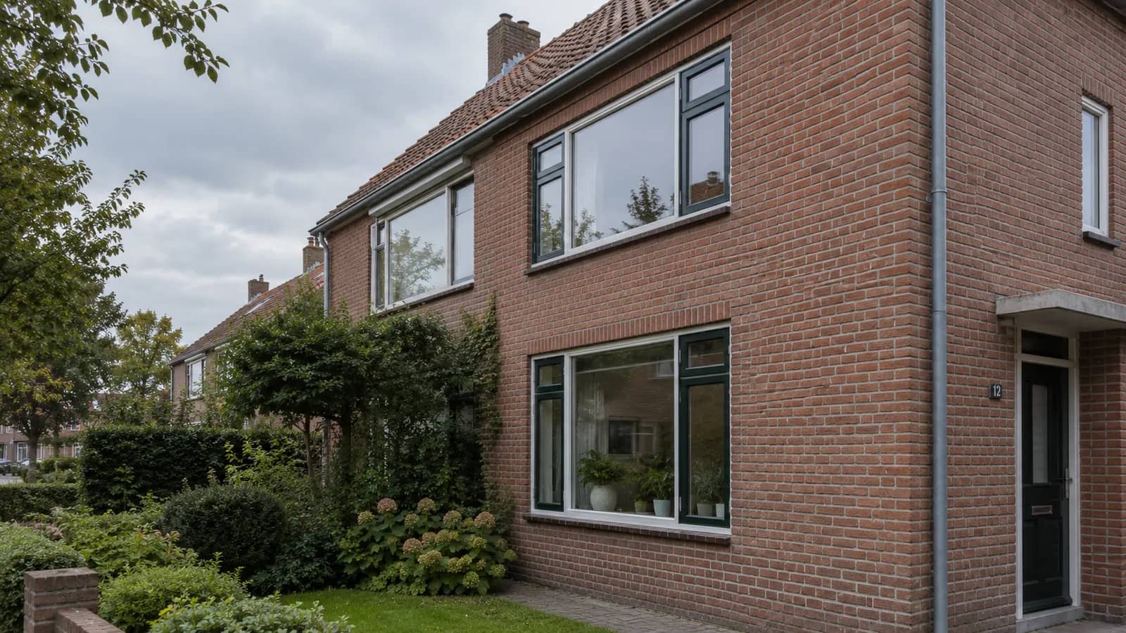 Bakstenen gevel van een woning met pannendak.